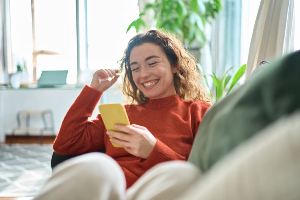 A woman smiling at her phone