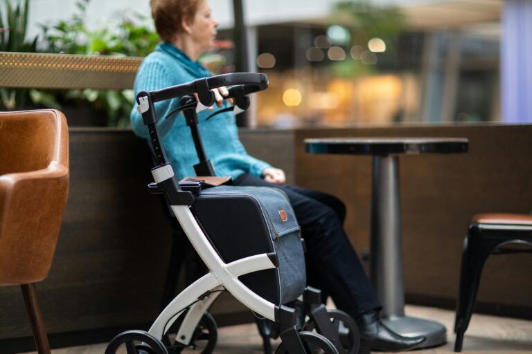 older woman sitting outside at a cafe with her walker