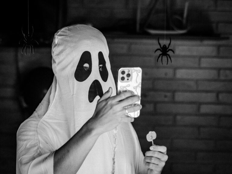 person in a ghost costume on their cell phone