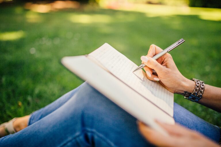 woman sitting in the grass and journaling