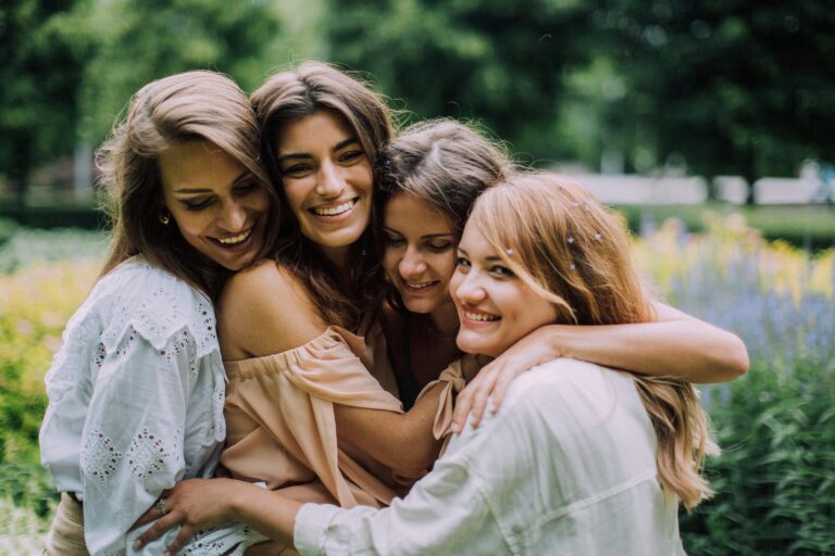 four young white women hugging in a garden